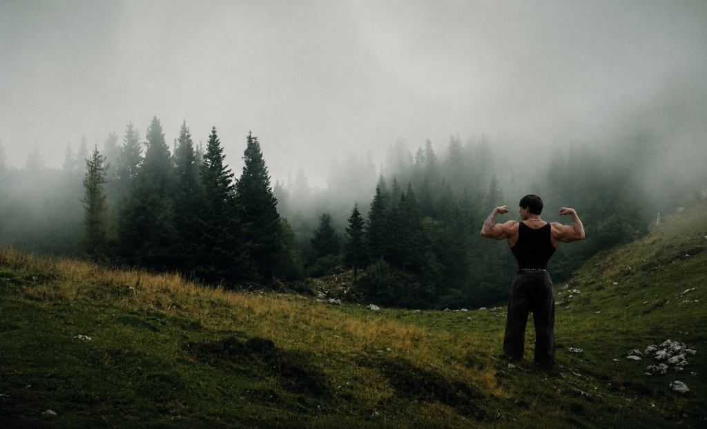 Bodybuilder flexing in mountain nature